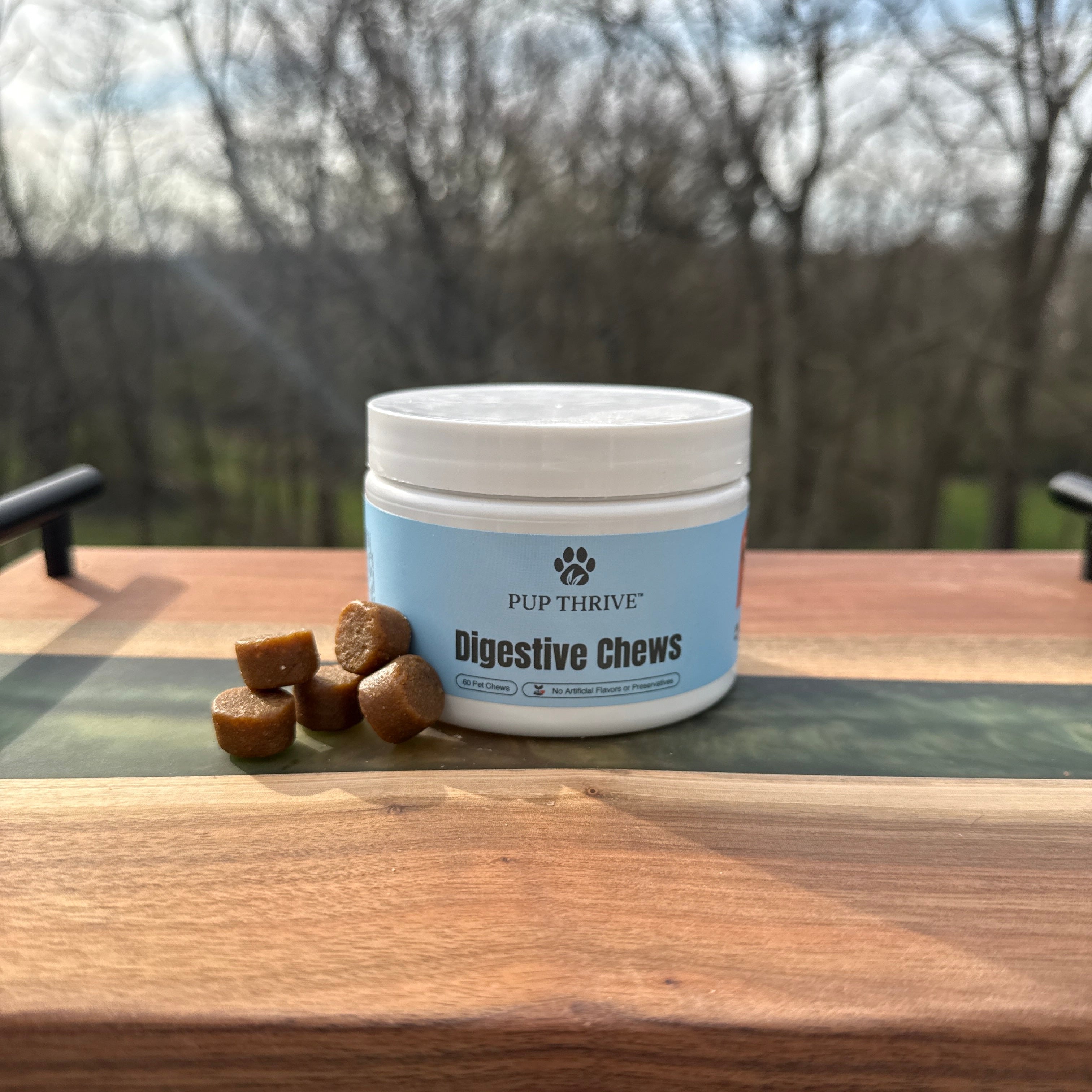 Container of Pet Thrive digestive chews on a wooden surface with outdoor background