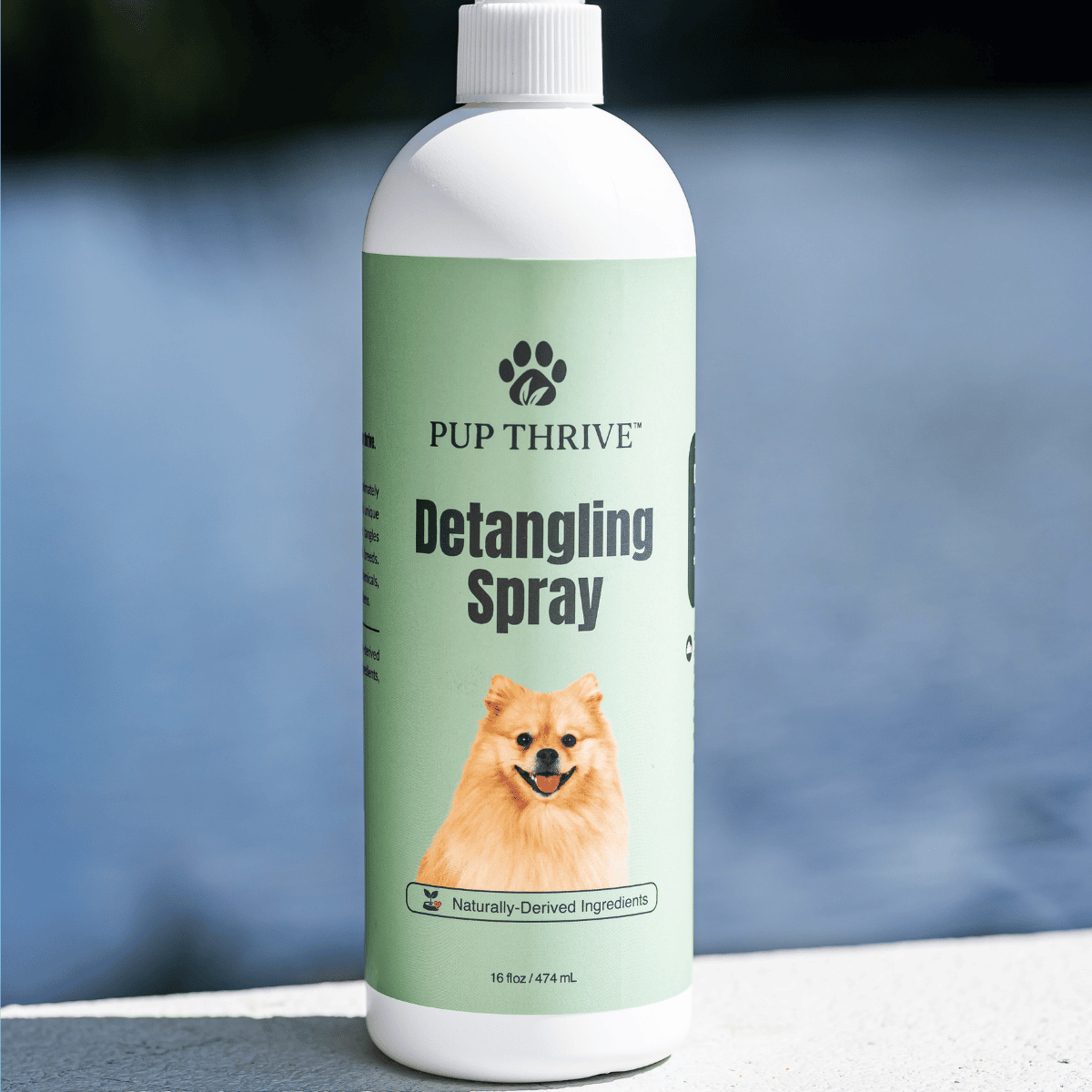 Bottle of Pup Thrive Detangling Spray with a dog on the label against a blurred background