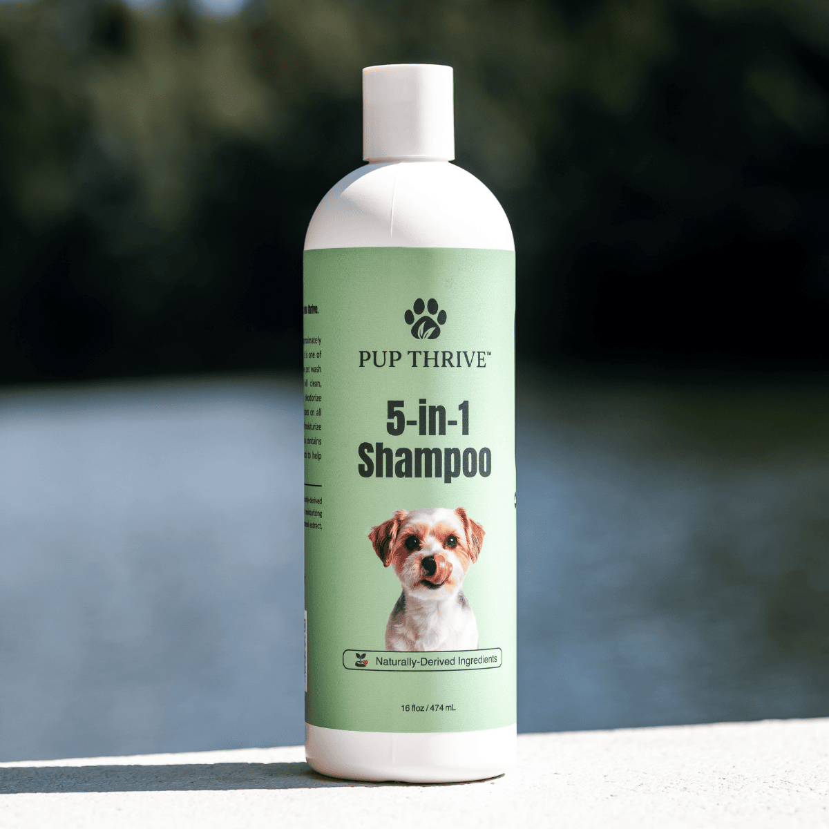 Pup Thrive 5-in-1 Shampoo bottle on a blurred natural background